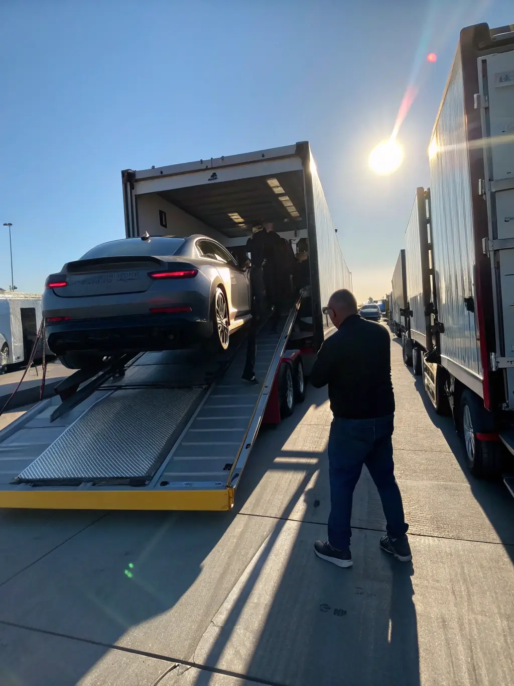A luxury car being carefully loaded onto an enclosed carrier, emphasizing the premium and expedited nature of the service.